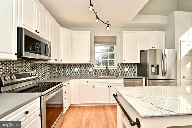a kitchen with granite countertop a refrigerator a sink a stove a microwave and wooden cabinets