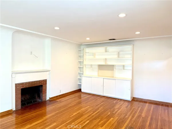 a view of empty room with wooden floor and fireplace
