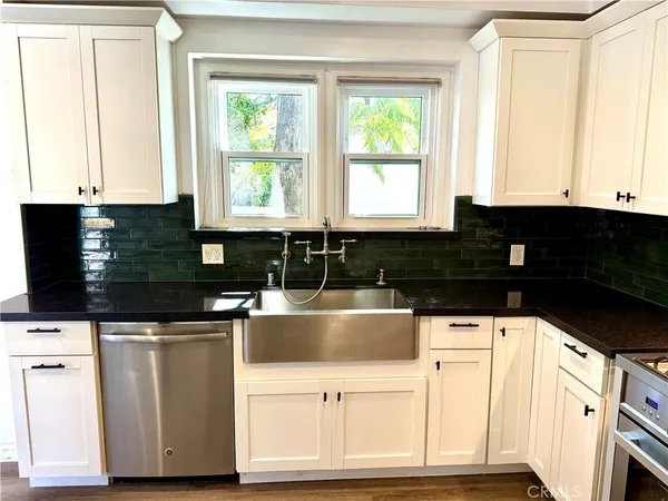 a kitchen with white cabinets and window