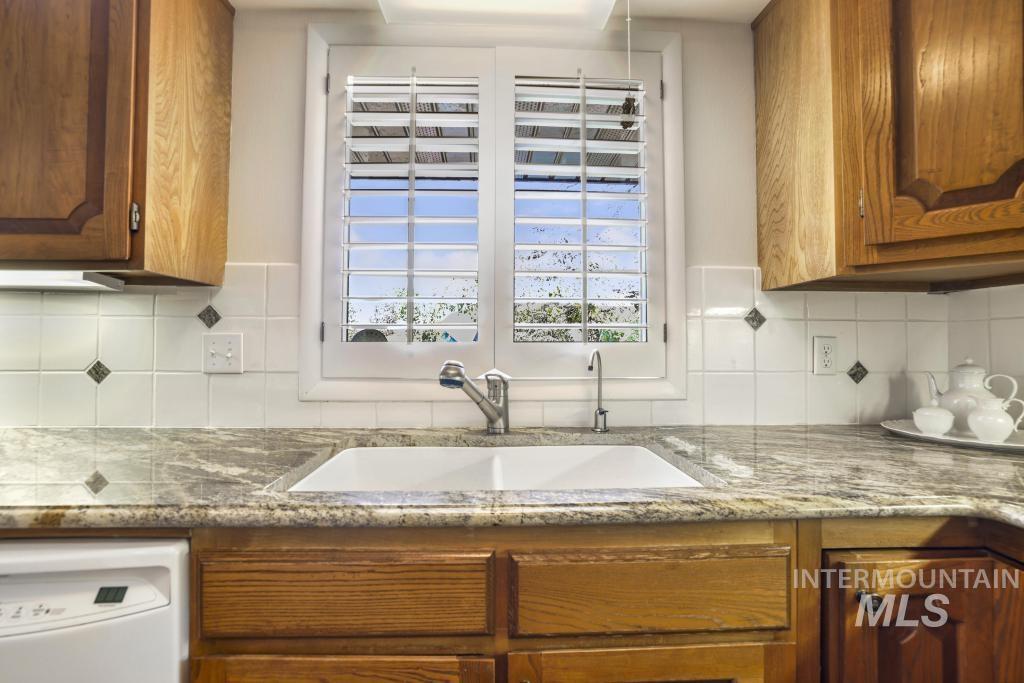 2018 Rancho Vista Drive Twin Falls, ID 83301 - Photo 13 of 50 Kitchen featuring a double-basin sink with a stainless steel faucet, wood-finish cabinetry, and solid surface countertops