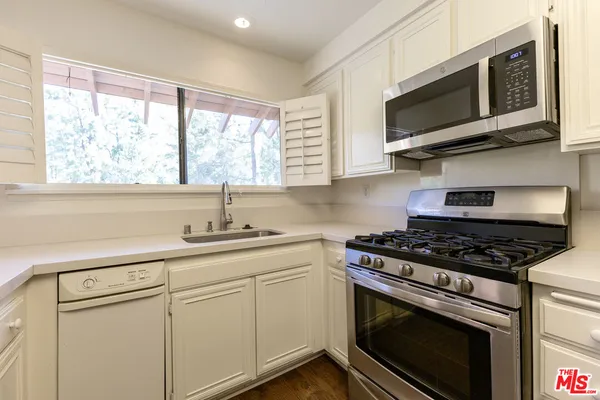 a kitchen with stainless steel appliances white cabinets granite counter tops and a window