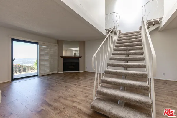 a view of a livingroom with wooden floor and stairs