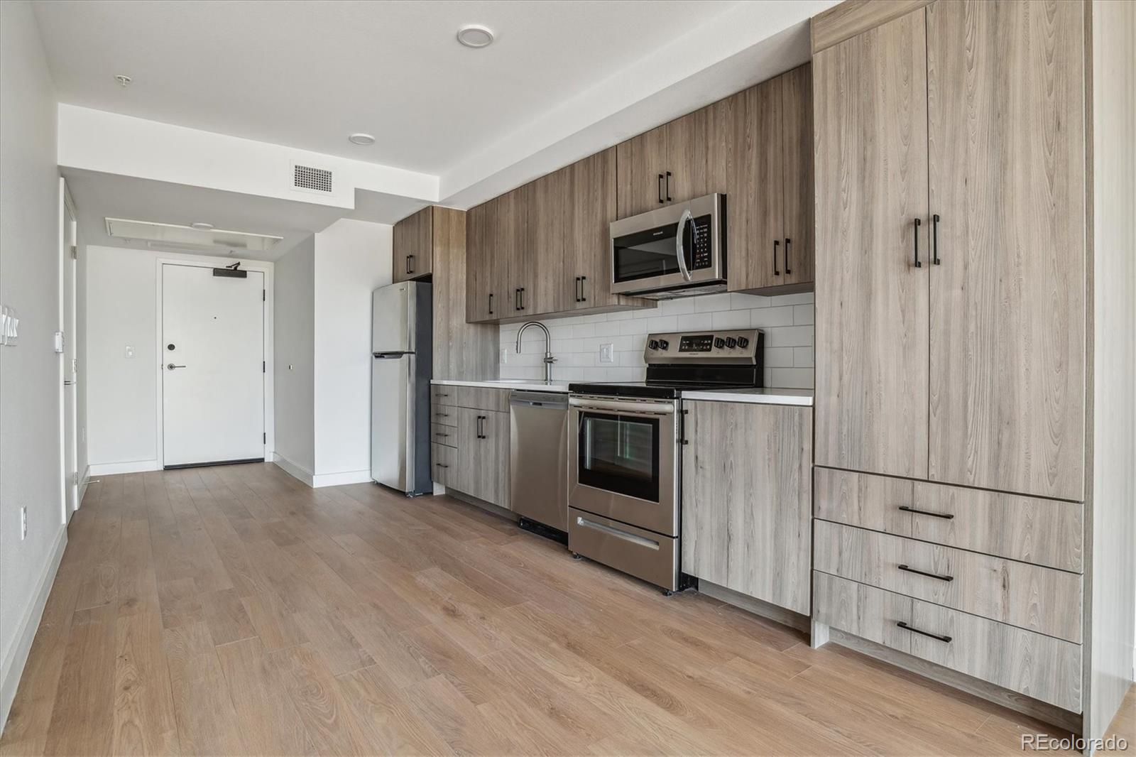 3575 Chestnut Place, Unit 301 Denver, CO 80216 - Photo 2 of 14 a kitchen with cabinets stainless steel appliances and wooden floor