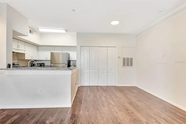 a view of an empty room with wooden floor and a window