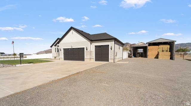 3678 Spiral Springs Road, Unit 204 Tooele, UT 84074 - Photo 1 of 59 Attached two-car garage with dark wood-finish doors, light-colored siding exterior, gray stone accents, and exterior wall sconces
