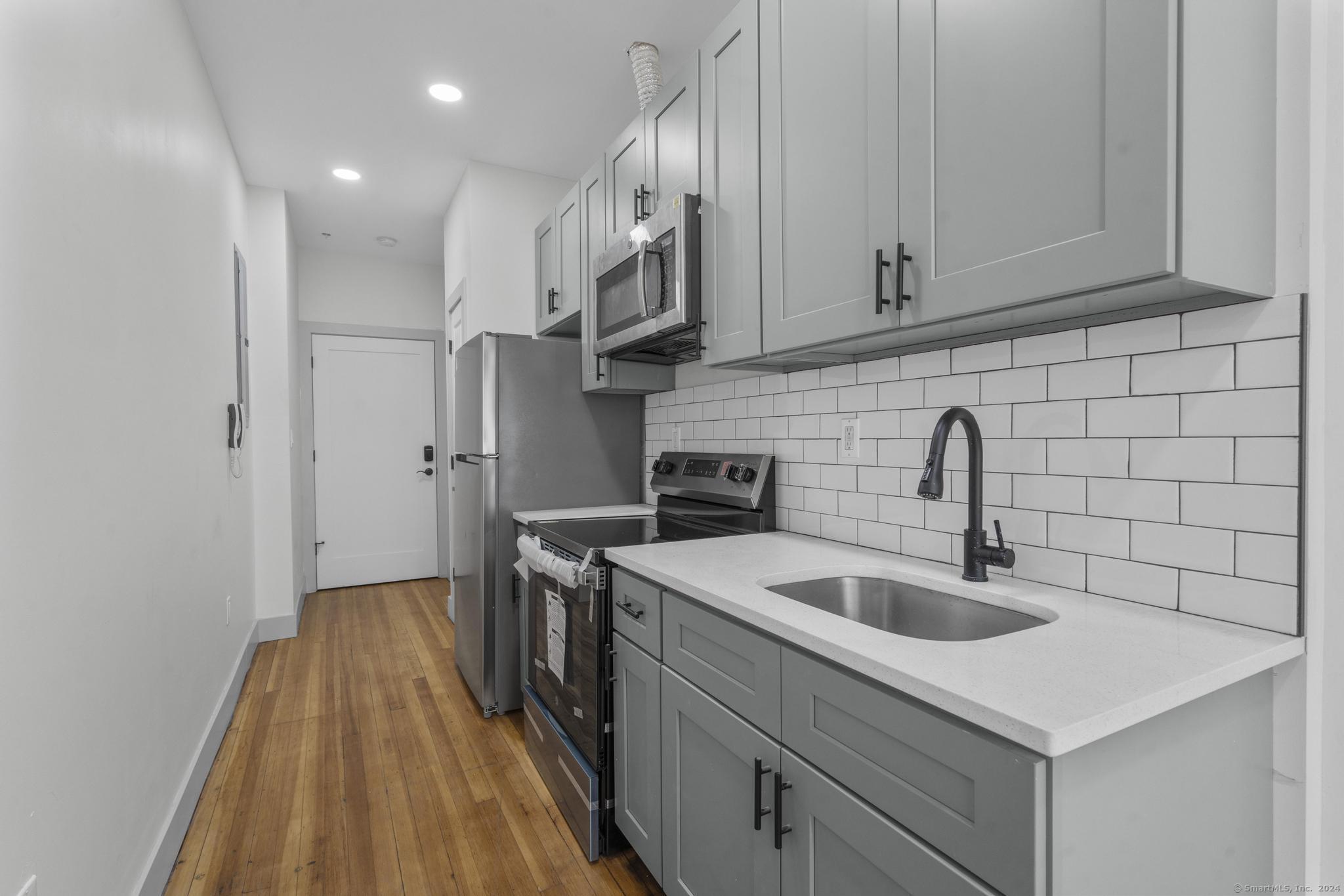 111 Bank Street, Unit 2A Waterbury, CT 06702 - Photo 2 of 16 a kitchen with stainless steel appliances granite countertop a sink stove and refrigerator