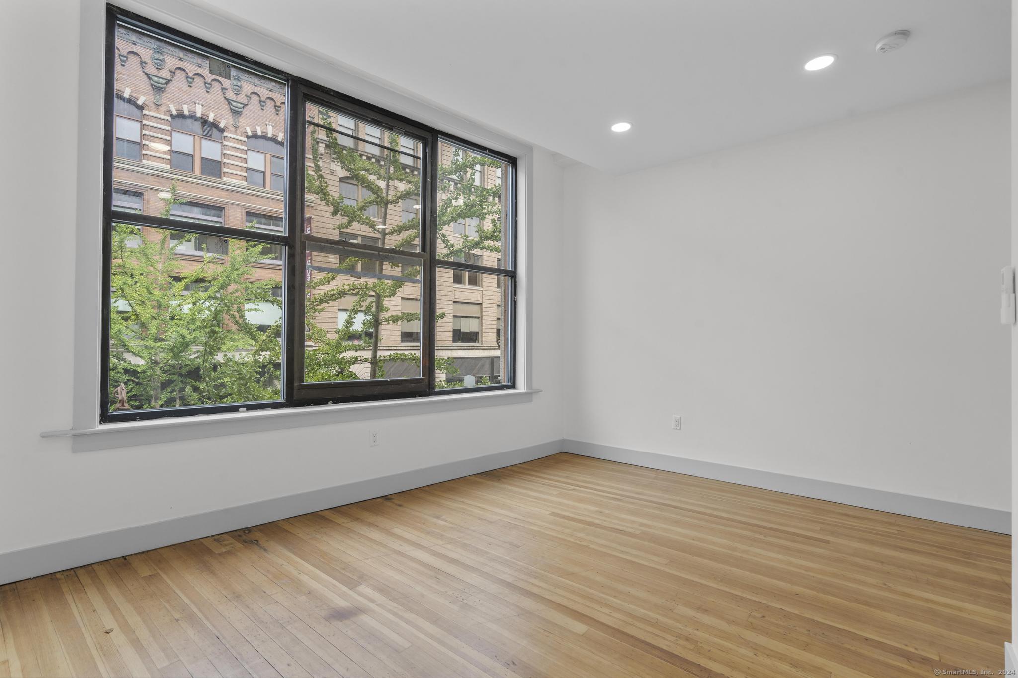 111 Bank Street, Unit 2A Waterbury, CT 06702 - Photo 5 of 16 a view of an empty room with wooden floor and a window