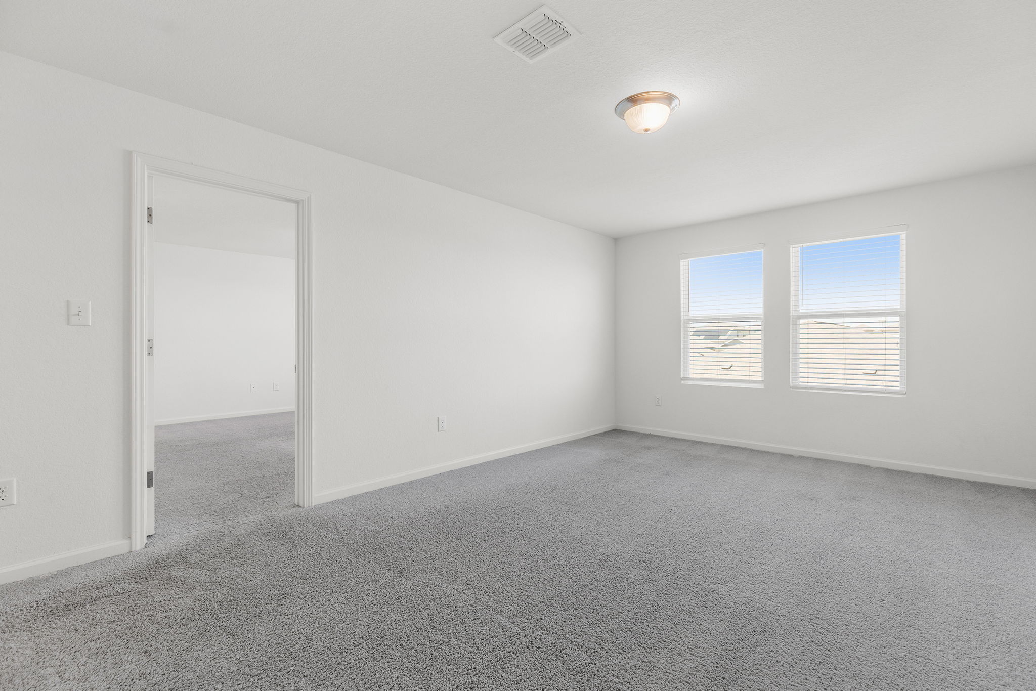 409 Line Of Fire Way Jarrell, TX 76537 - Photo 15 of 30 Spacious room featuring light gray carpeting, neutral white walls, two windows with horizontal blinds, flush-mount ceiling light fixture, white trim, and open doorway access.