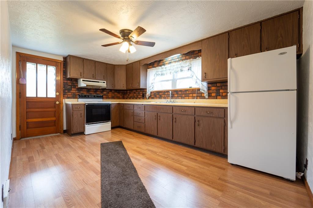 1590 New Stanton Ruffsdale Road Ruffs Dale, PA 15679 - Photo 5 of 16 a kitchen with stainless steel appliances granite countertop a refrigerator a sink dishwasher a stove with wooden cabinets and floors