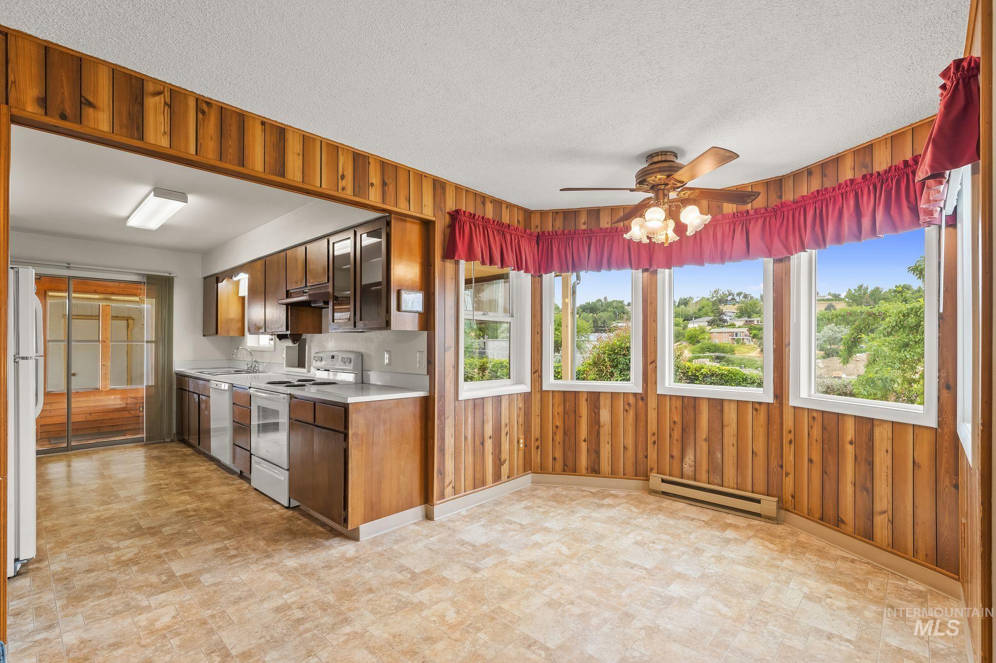 1721 3rd Street Lewiston, ID 83501 - Photo 31 of 45 Kitchen and dining area featuring wood-paneled walls, multiple windows, a ceiling fan with integrated lighting, and resilient flooring