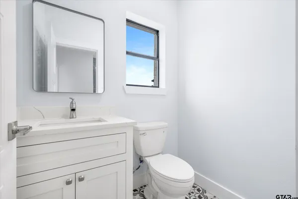 a bathroom with a toilet sink vanity and mirror