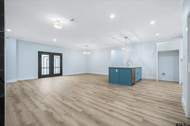 a view of an empty room with wooden floor and kitchen