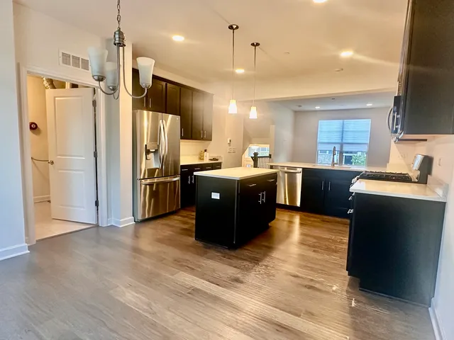 a kitchen with stainless steel appliances kitchen island granite countertop a refrigerator and a sink