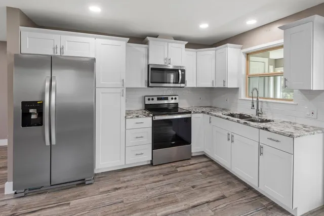 a kitchen with granite countertop a refrigerator stove and sink
