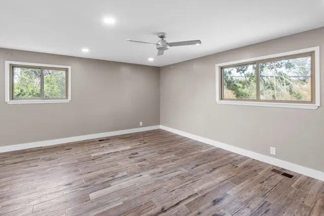 a view of an empty room with wooden floor and a window