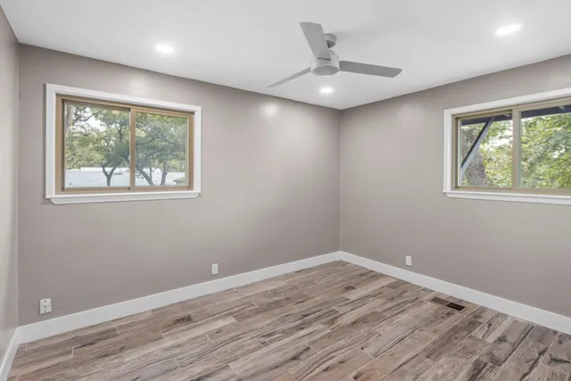 a view of an empty room with wooden floor and a window