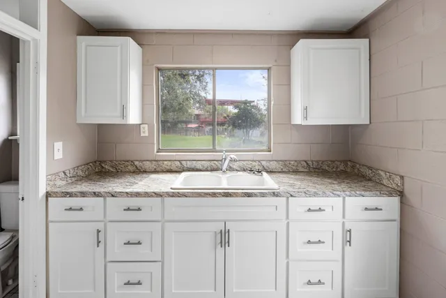 a kitchen with granite countertop a sink window and cabinets