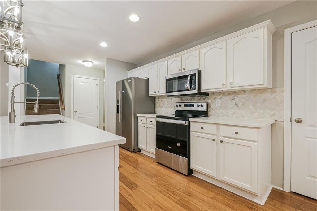 75 Pebble Crossing Covington, GA 30016 - Photo 9 of 27 a kitchen with a sink a stove a refrigerator and white cabinets