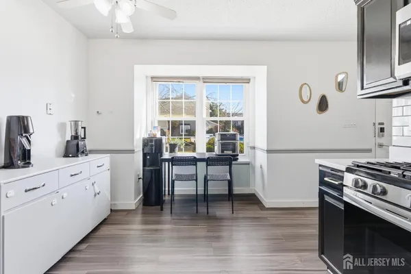 a kitchen with white cabinets and wooden floor