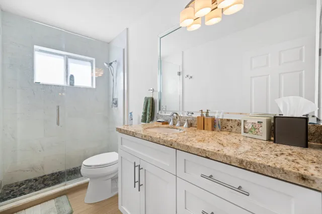 a bathroom with a granite countertop sink a toilet and mirror