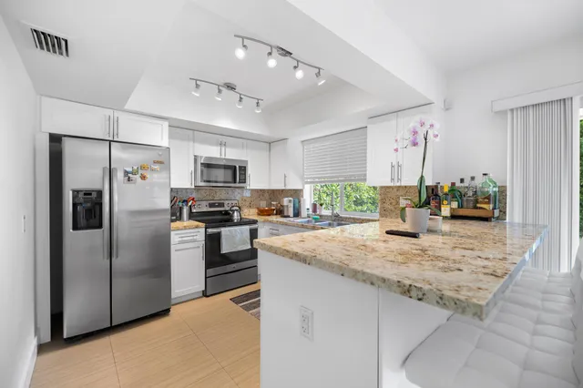 a kitchen with stainless steel appliances granite countertop a refrigerator a stove a sink a microwave oven with a dining table and chairs