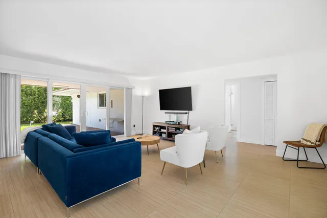 a living room with furniture flat screen tv and a large window