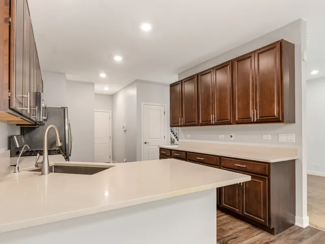 a kitchen with stainless steel appliances a sink a stove a refrigerator cabinets and wooden floor