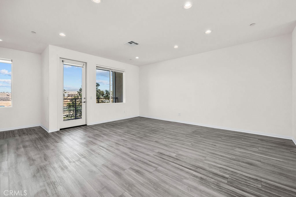 159 Steely Irvine, CA 92614 - Photo 3 of 30 Spacious living area featuring luxury vinyl flooring and recessed lighting with balcony access.