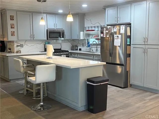 a kitchen with stainless steel appliances granite countertop a refrigerator a stove a sink and a microwave