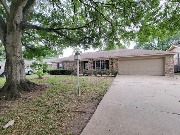 a front view of a house with a yard and a large tree