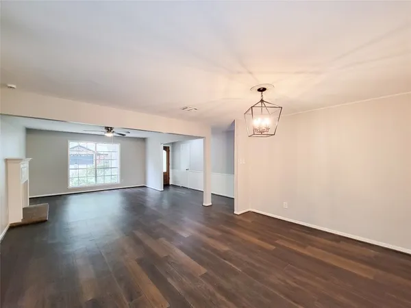 a view of an empty room with wooden floor and windows