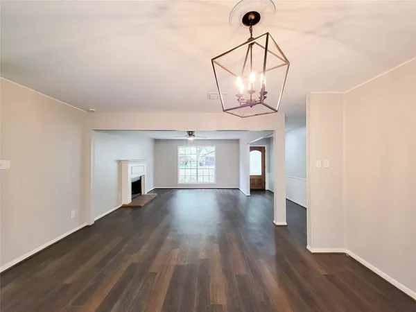 a view of a room with wooden floor chandelier and windows