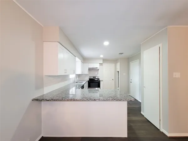 a large kitchen with granite countertop a sink and a refrigerator
