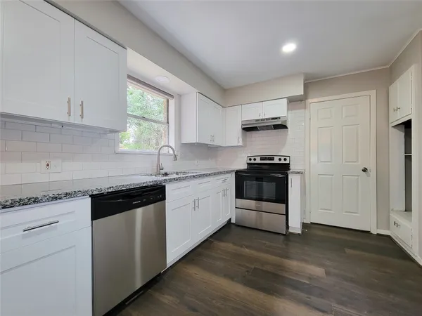 a kitchen with granite countertop a refrigerator and a stove top oven