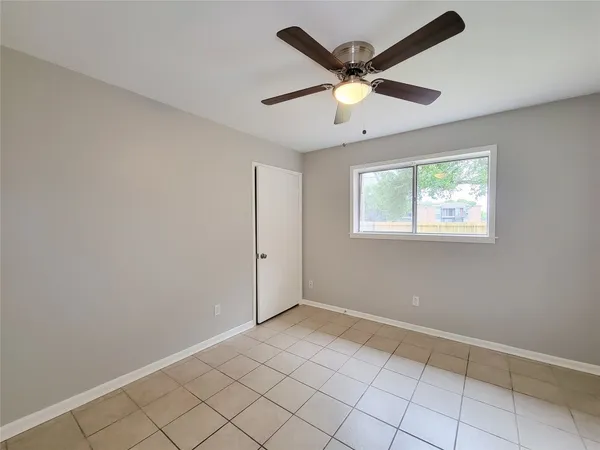 an empty room with windows and fan