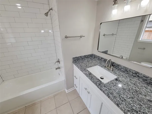 a bathroom with a granite countertop sink a mirror and a bathtub