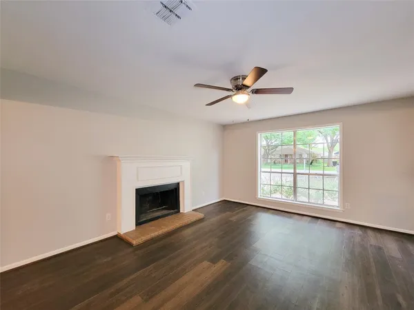 an empty room with wooden floor fireplace and windows
