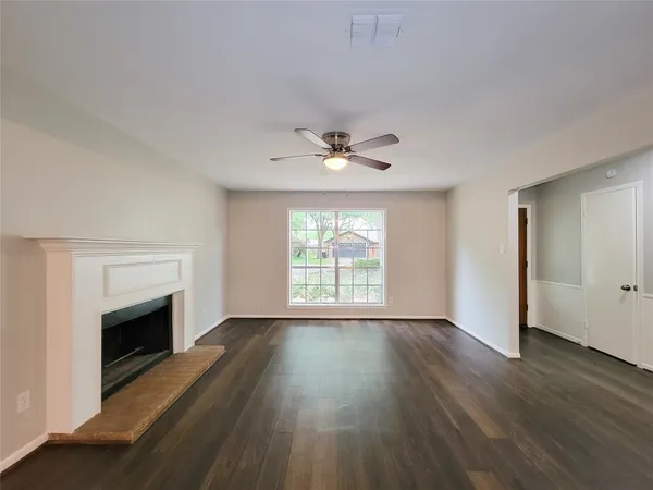 an empty room with wooden floor fireplace and windows