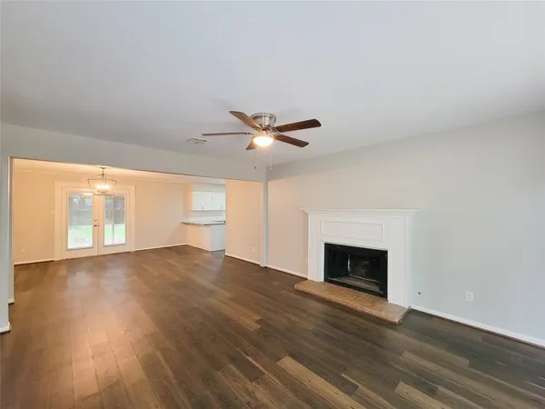an empty room with wooden floor fireplace and windows