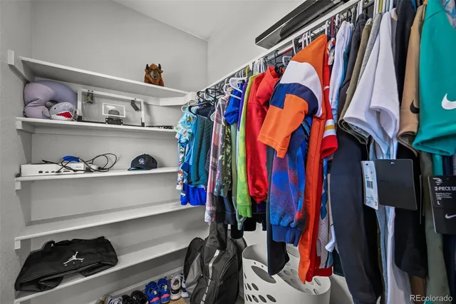a view of walk in closet with clothes and shoes