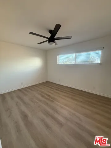 an empty room with wooden floor fan and windows