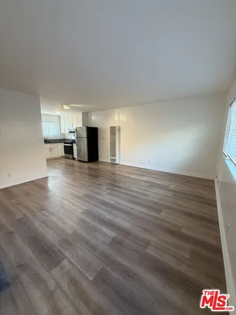 a view of empty room with wooden floor and window