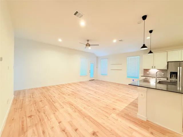 a view of a kitchen with kitchen island a sink wooden floor and counter top space
