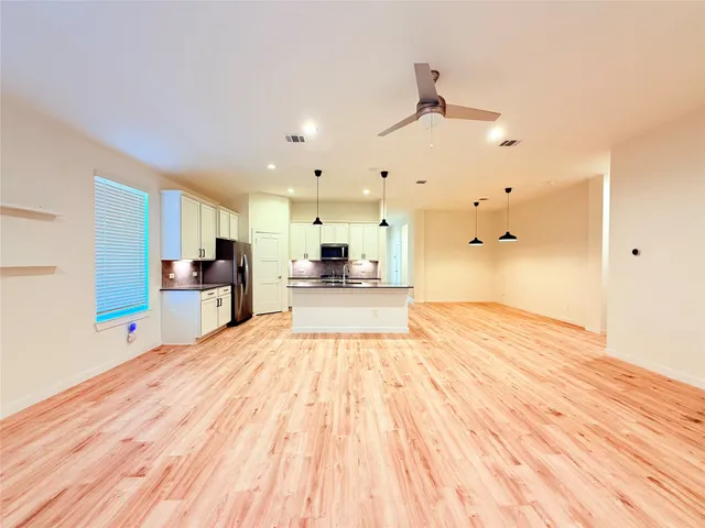 a view of a living room with kitchen island wooden floor and appliances