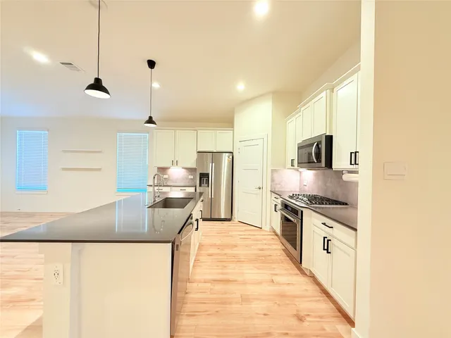 a large kitchen with stainless steel appliances granite countertop a stove a sink and a refrigerator