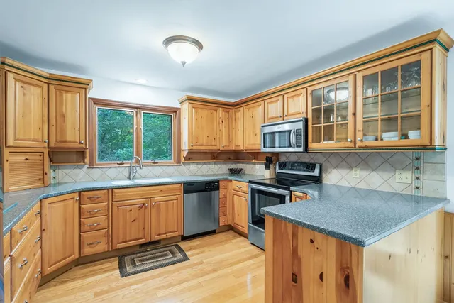 a kitchen with stainless steel appliances granite countertop a stove top oven a sink dishwasher a dining table and chairs with wooden floor