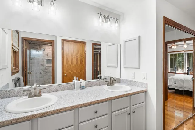 a bathroom with a sink double vanity granite tub shower and a mirror