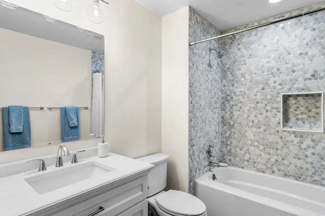 a bathroom with a bathtub shower sink vanity and toilet