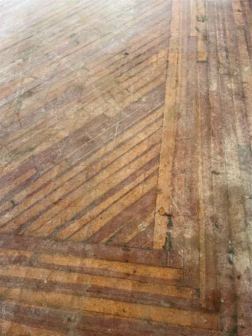 a view of an empty room with wooden floor and windows