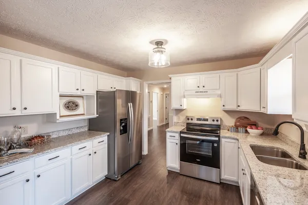 a kitchen with granite countertop a refrigerator stove and sink with wooden floor